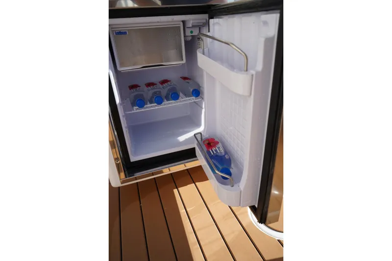 Slide: The Image of Open mini fridge on 2024 Edgewater 285CC boat, stocked with water bottles. - 9