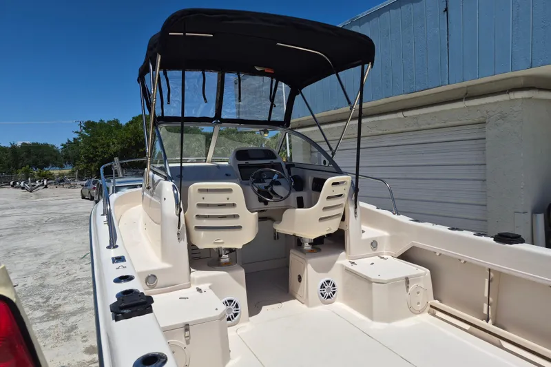 Slide: The Image of 2022 Grady-White Adventure 208 boat with canopy, steering wheel, and seating, docked outdoors. - 12