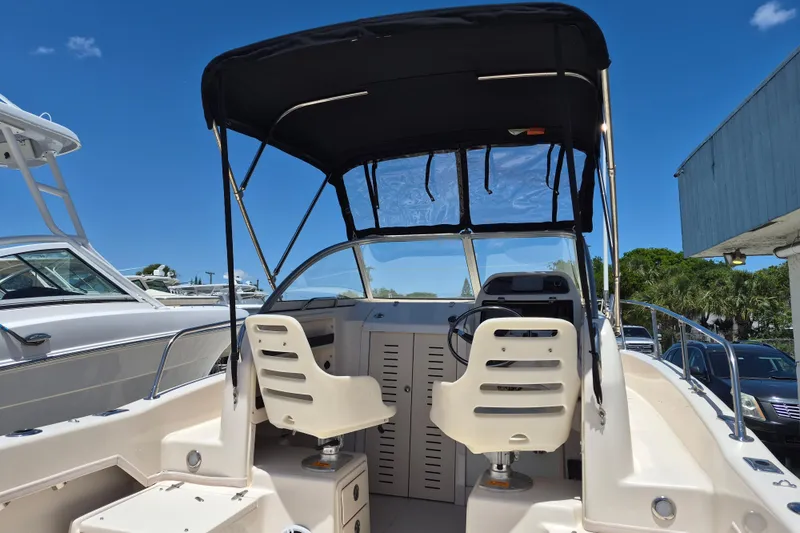 Slide: The Image of 2022 Grady-White Adventure 208 boat interior with dual seats and canopy under clear blue sky. - 5