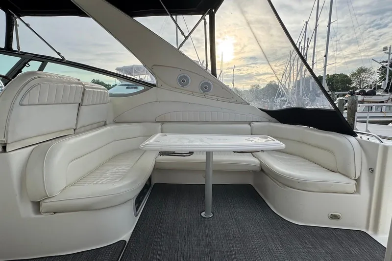 Slide: The Image of 1998 Maxum 4100 SCR yacht interior with white seating and table, docked at marina. - 2