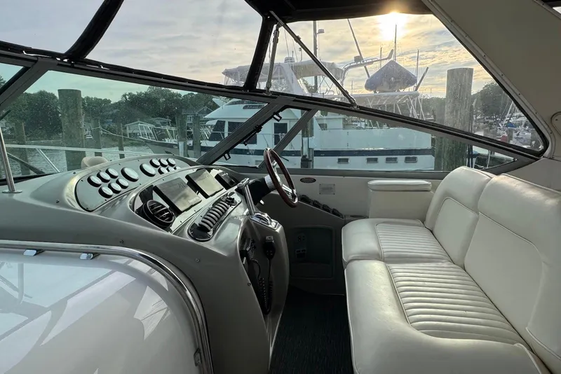 Slide: The Image of 1998 Maxum 4100 SCR yacht interior with helm and white seating at marina. - 5