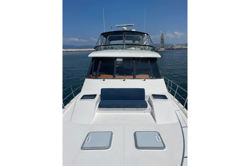 Slide: The Image of 2001 Bayliner 4788 Pilot House Motoryacht on calm water, showcasing sleek design and spacious deck. - 3