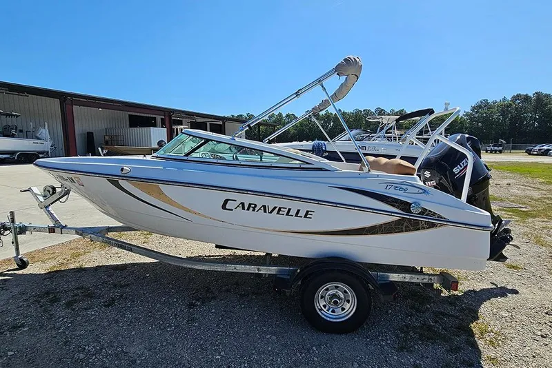 Slide: The Image of 2019 Caravelle 17 EBo Bowrider boat on trailer, parked outdoors under clear blue sky. - 6