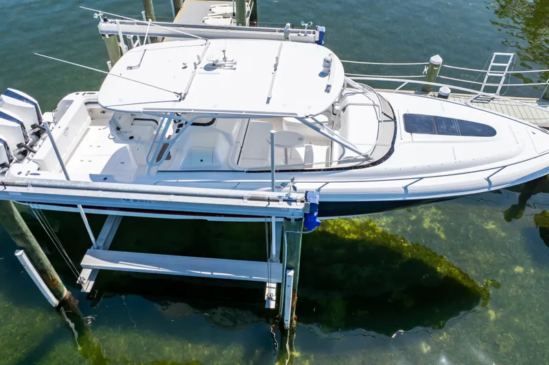 Slide: The Image of 2014 Intrepid 375 Walkaround boat docked on a lift over clear water. - 30