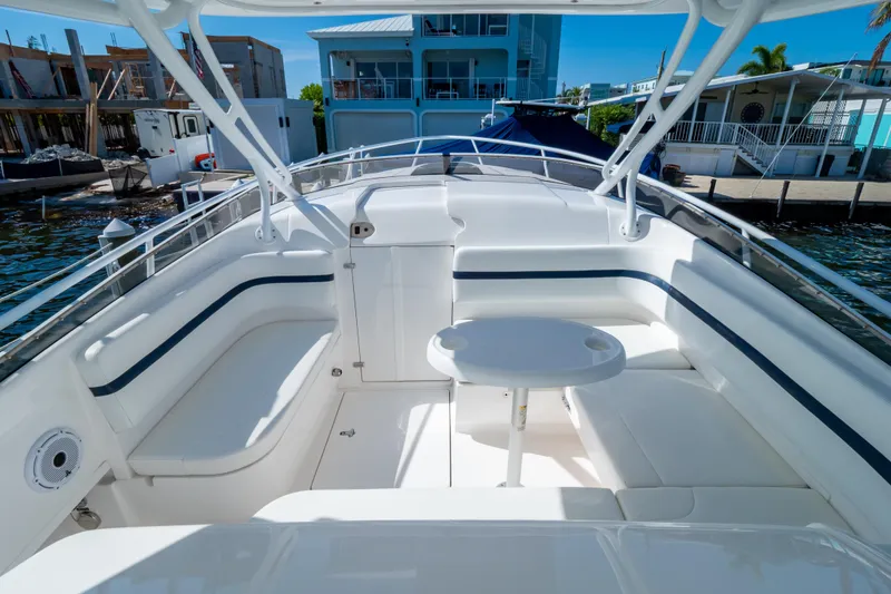 Slide: The Image of 2014 Intrepid 375 Walkaround boat interior with seating and table, docked by waterfront homes. - 5