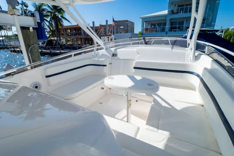 Slide: The Image of 2014 Intrepid 375 Walkaround boat interior with seating and table, docked near waterfront homes. - 52