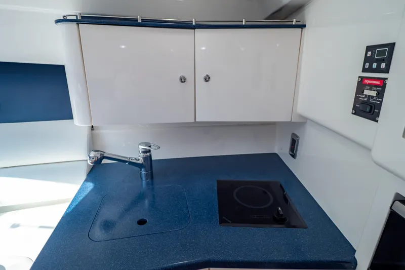 Slide: The Image of 2014 Intrepid 375 Walkaround boat kitchen with blue countertop, sink, and stove. - 57