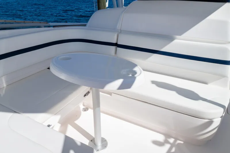 Slide: The Image of 2014 Intrepid 375 Walkaround boat seating area with white cushions and small table. - 89