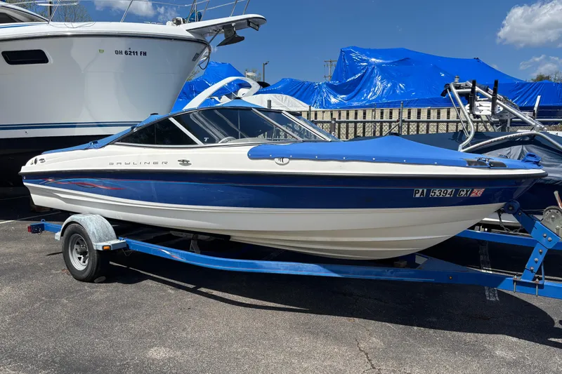 The Image of 2006 Bayliner 205 boat on trailer, blue and white design, parked outdoors. - 0
