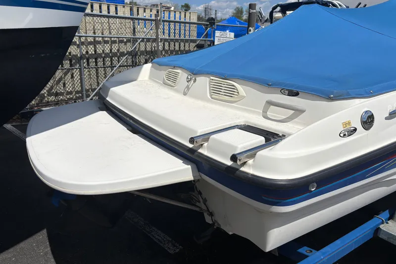 Slide: The Image of 2006 Bayliner 205 boat with blue cover, docked in a marina. - 2