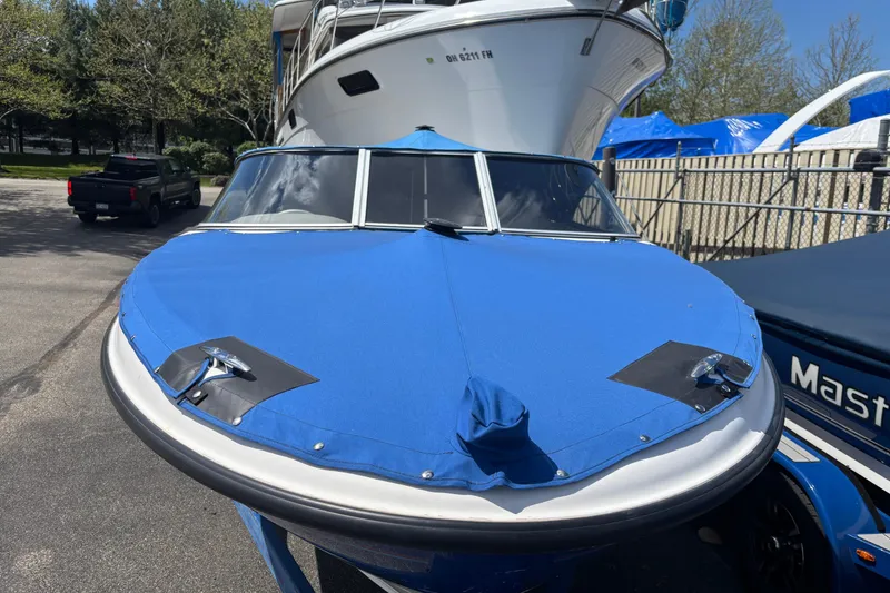 Slide: The Image of 2006 Bayliner 205 boat with blue cover, parked outdoors. - 3
