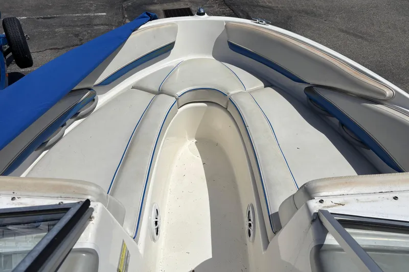 Slide: The Image of 2006 Bayliner 205 boat interior with white and blue seating, docked outdoors. - 5