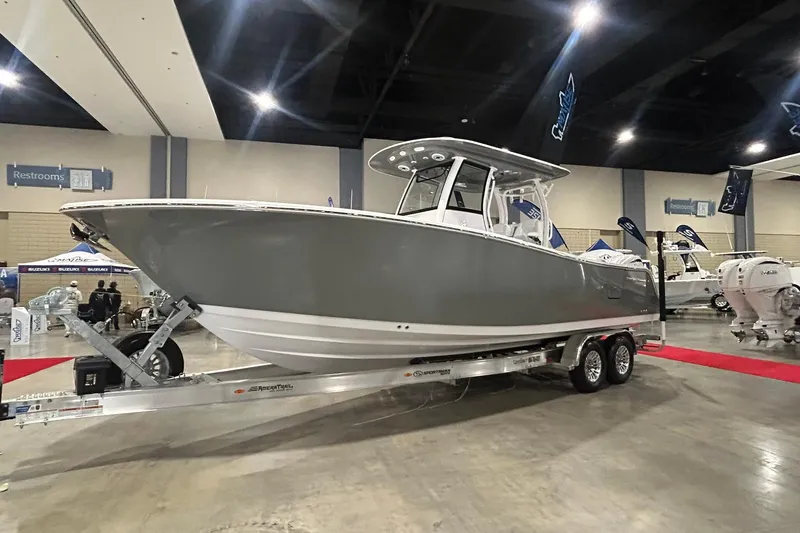 The Image of 2026 Sportsman Open 282 Center Console boat displayed indoors on a trailer. - 1