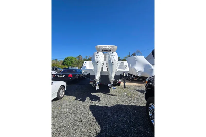 Slide: The Image of 2025 Sea Hunt Gamefish 28 Coffin Box boat with dual outboard engines in a parking lot. - 2