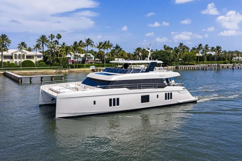 Slide: The Image of 2024 Sunreef 80 Power yacht cruising near luxury waterfront homes. - 14