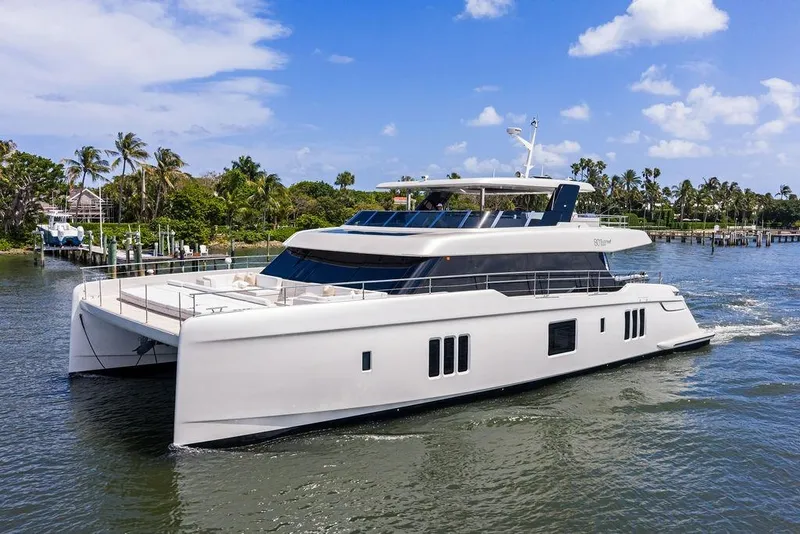 Slide: The Image of 2024 Sunreef 80 Power yacht cruising on a sunny day near palm-lined shore. - 2