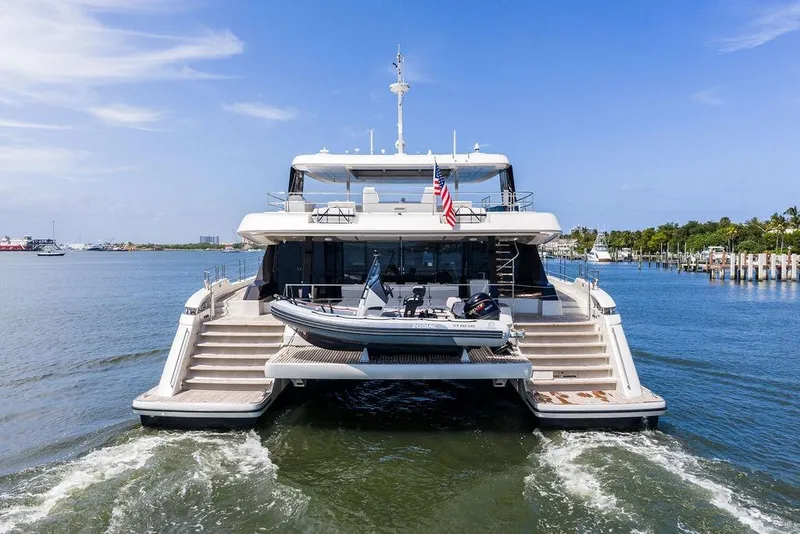 Slide: The Image of 2024 Sunreef 80 Power yacht on water, rear view with tender boat and American flag. - 4