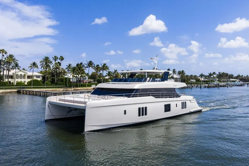 Slide: The Image of Luxury Sunreef 80 Power yacht cruising near palm-lined waterfront homes, 2024 model. - 5