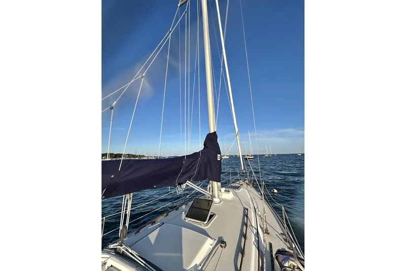 The Image of 1984 Pearson 34 sailboat on stands, outdoors, with clear blue sky background. - 0