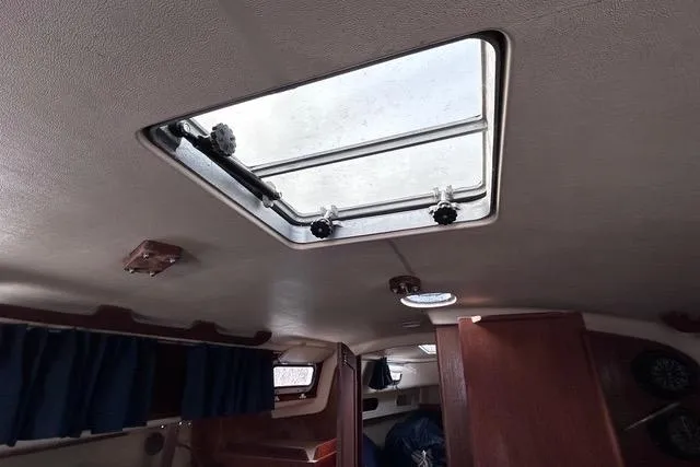Slide: The Image of Interior of a 1984 Pearson 34 sailboat with a window and blue curtain. - 11