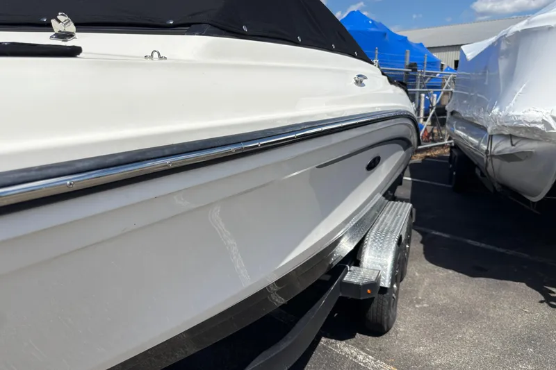 Slide: The Image of 2024 Sea Ray SPX 210 boat on trailer, side view, in a marina setting. - 2