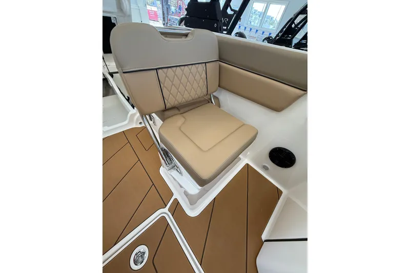 Slide: The Image of 2026 Bayliner D22 boat interior with tan cushioned seating and wood-patterned flooring. - 7