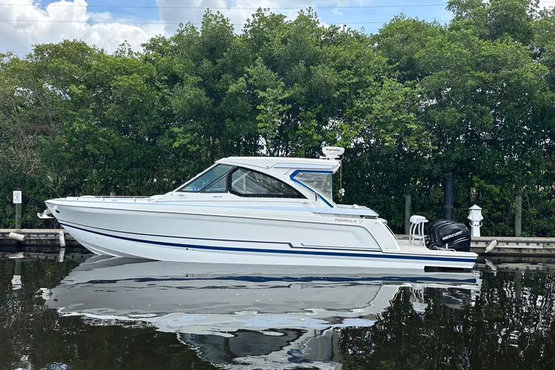 The Image of 2021 Formula 380 Super Sport Crossover OB boat on calm water, surrounded by greenery. - 0