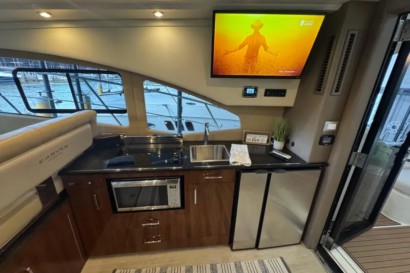 Slide: The Image of Interior of 2016 Carver C37 Coupe yacht with kitchenette and TV display. - 13