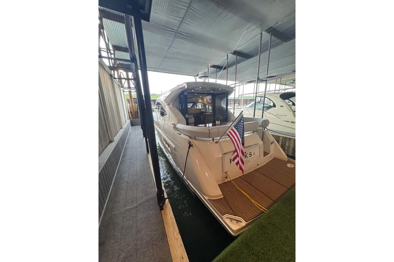 Slide: The Image of 2016 Carver C37 Coupe yacht docked, featuring American flag and spacious deck. - 32