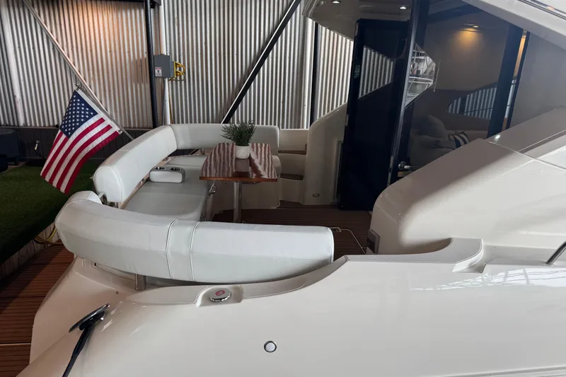 Slide: The Image of 2016 Carver C37 Coupe yacht with American flag and elegant seating area. - 36