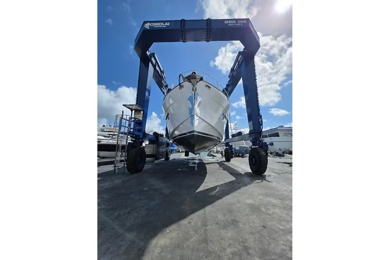 Slide: The Image of 2024 Sirena 58 Flybridge MY yacht lifted by a large crane under a clear sky. - 85