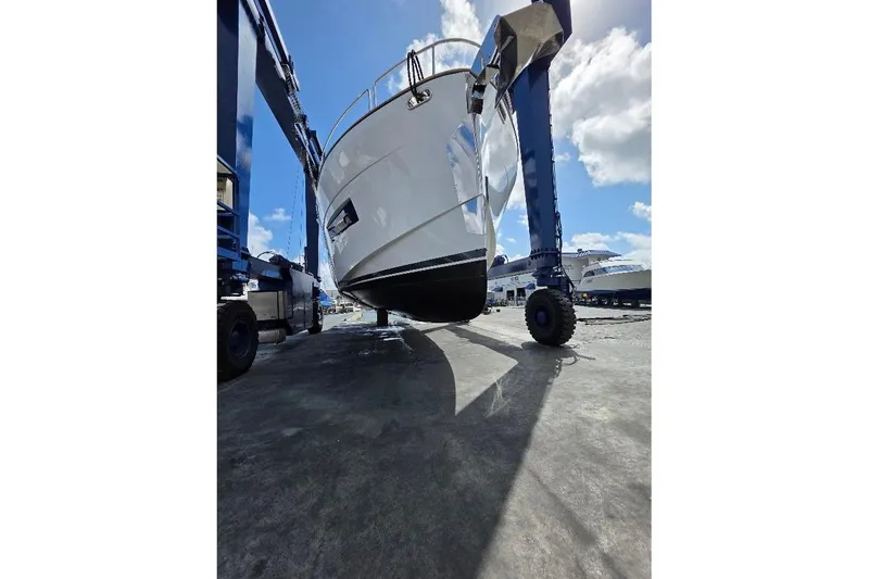 Slide: The Image of 2024 Sirena 58 Flybridge MY yacht on a lift under a bright blue sky. - 86