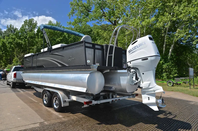 Slide: The Image of 2022 Qwest E822 pontoon boat with Suzuki outboard motor on trailer, surrounded by trees. - 12