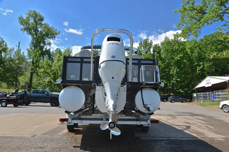 Slide: The Image of 2022 Qwest E822 boat on trailer, rear view, with outboard motor, surrounded by trees. - 13