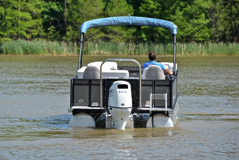 Slide: The Image of 2022 Qwest E822 pontoon boat cruising on a serene lake with lush greenery. - 7