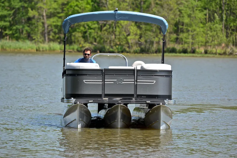 Slide: The Image of 2022 Qwest E822 pontoon boat cruising on a serene lake with lush greenery. - 9
