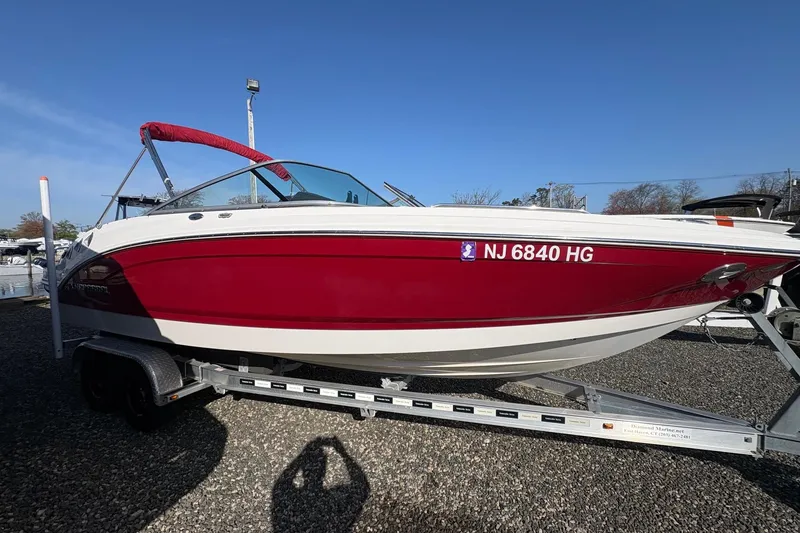Slide: The Image of 2015 Chaparral 246 SSi boat in red and white on a trailer, clear sky background. - 2