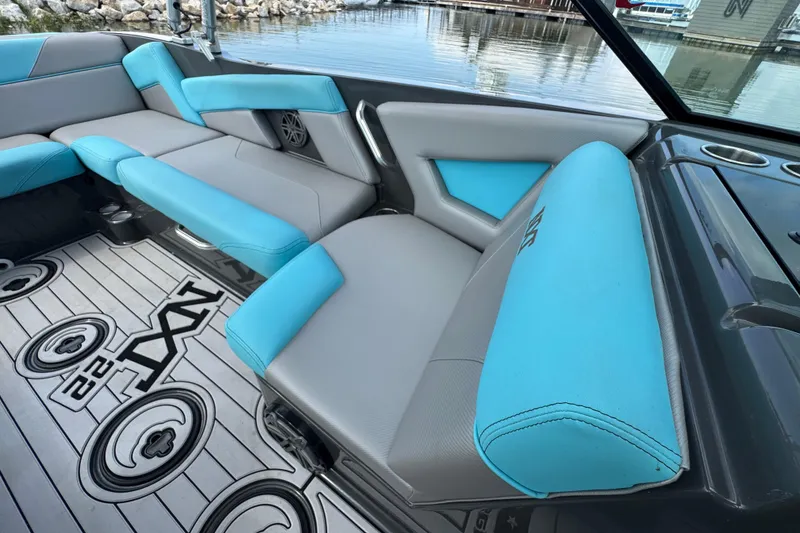 Slide: The Image of 2017 MasterCraft NXT22 interior with blue and gray seating, docked by the water. - 10