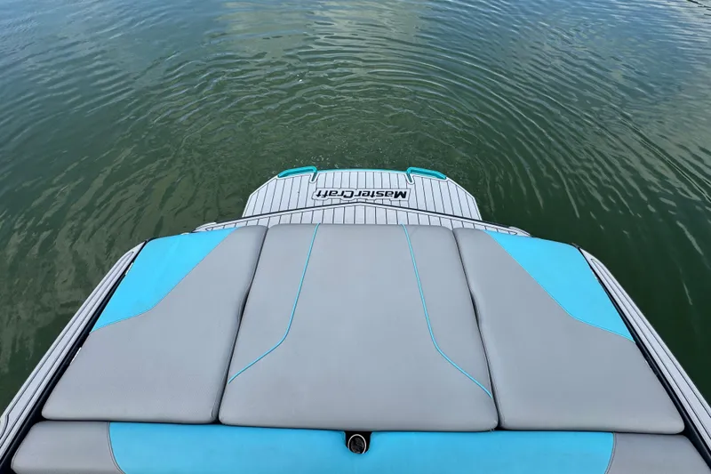 Slide: The Image of 2017 MasterCraft NXT22 boat with gray and blue seating on calm water. - 18