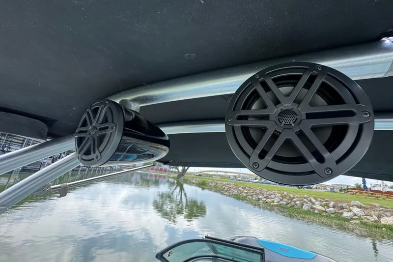 Slide: The Image of 2017 MasterCraft NXT22 boat speakers mounted under canopy by the water. - 21