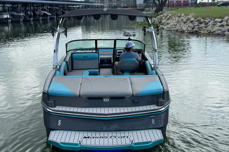 Slide: The Image of 2017 MasterCraft NXT22 boat on water, rear view with driver. - 4