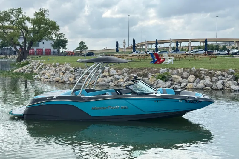 Slide: The Image of 2017 MasterCraft NXT22 boat on calm water near a rocky shoreline. - 5