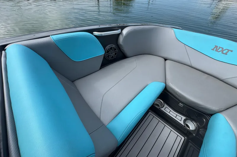 Slide: The Image of 2017 MasterCraft NXT22 boat interior with blue and gray seating, near water. - 7