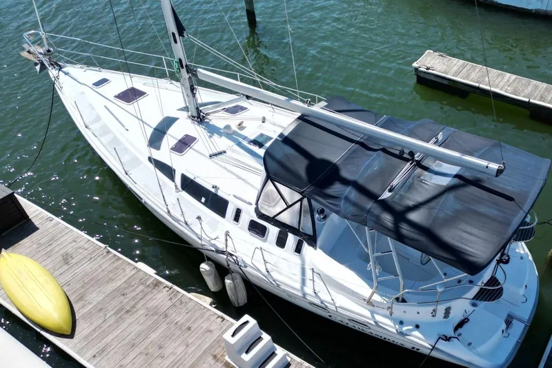Slide: The Image of Sailboat docked at marina, Hunter 410 model, year 2000, with canopy and kayak nearby. - 6