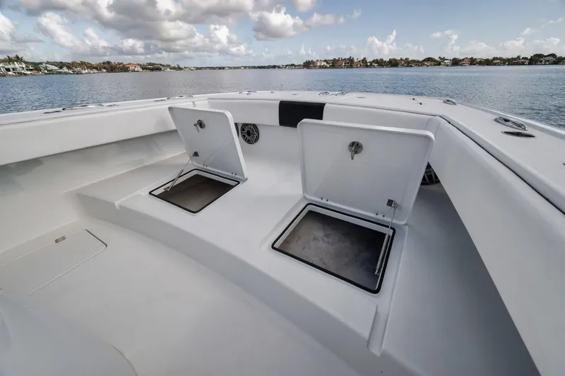 Slide: The Image of Freeman 42LR 2020 boat deck with open storage compartments on a calm lake. - 21