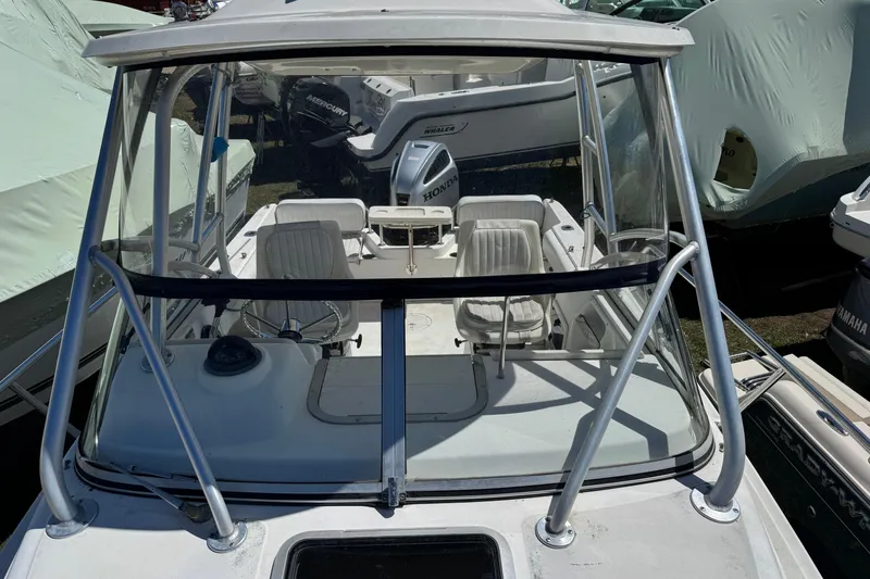Slide: The Image of 2000 Boston Whaler 21 Conquest boat with Honda outboard motor, docked among other boats. - 11