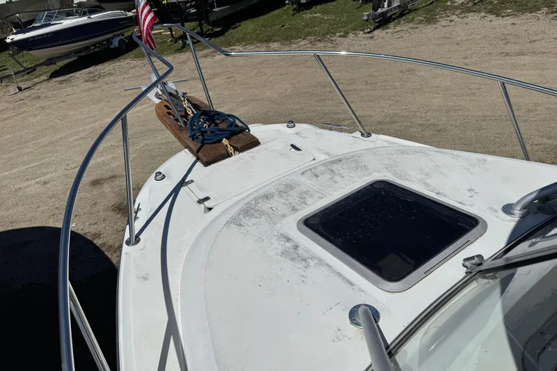 Slide: The Image of 2000 Boston Whaler 21 Conquest boat deck with railing and hatch, parked on sandy ground. - 12