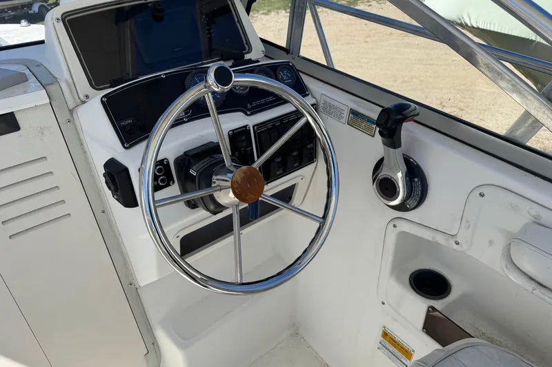 Slide: The Image of Steering console of a 2000 Boston Whaler 21 Conquest boat, featuring controls and gauges. - 4