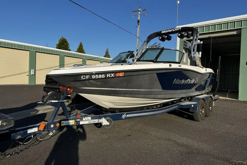 The Image of 2016 MasterCraft X10 boat on trailer, parked outdoors near storage units. - 0