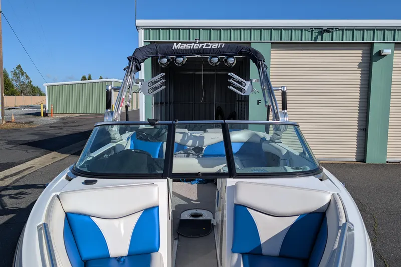 Slide: The Image of 2016 MasterCraft X10 boat with blue and white interior, parked near storage units. - 19